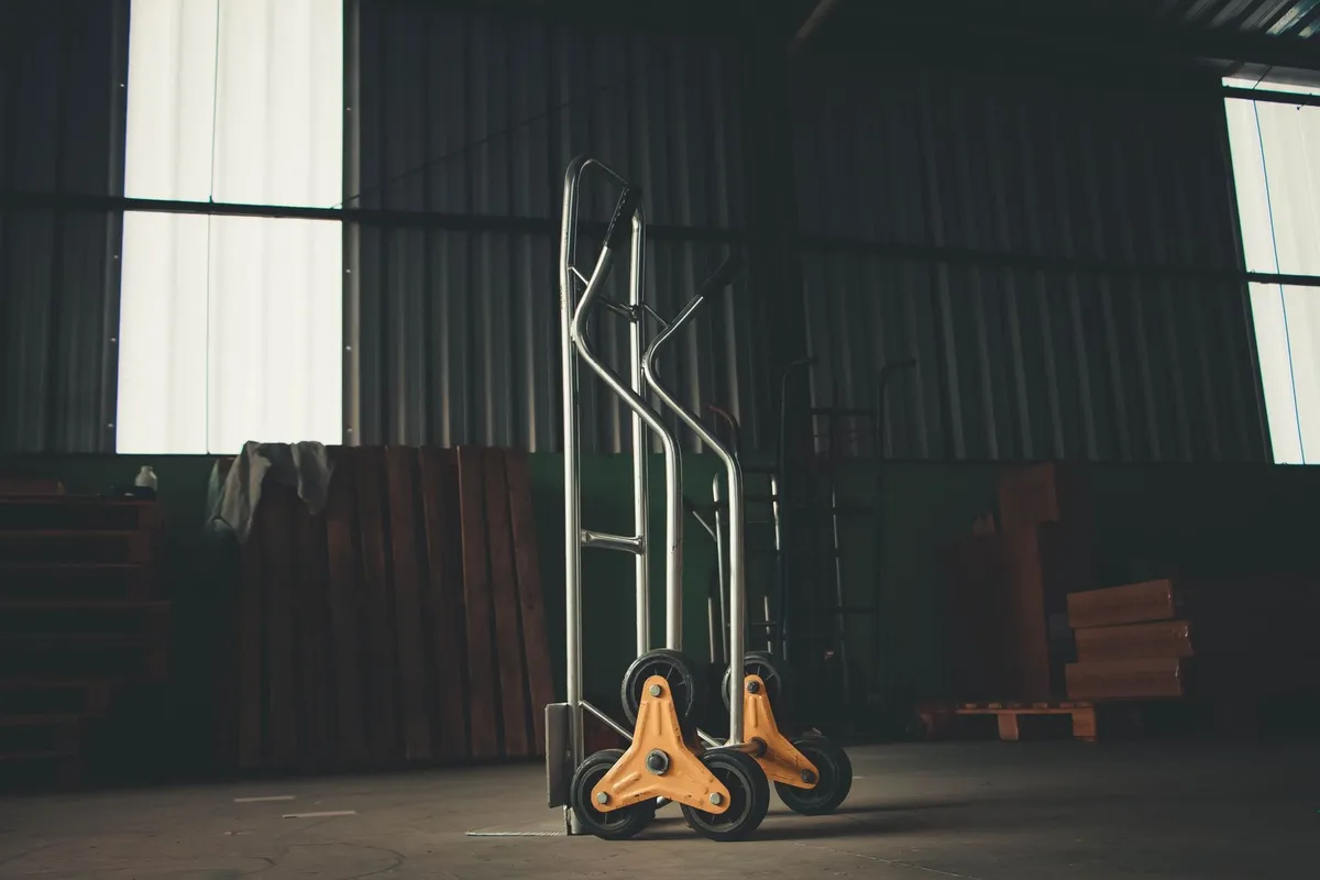 A metal hand truck in a dimly lit warehouse, symbolizing the logistics of piano removal.